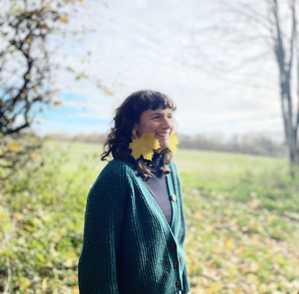 Slightly blurry image of Sophie outdoors with autumn leaves as earrings