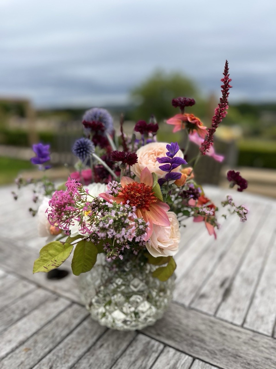 Vase of cut summer garden flowers on a garden table