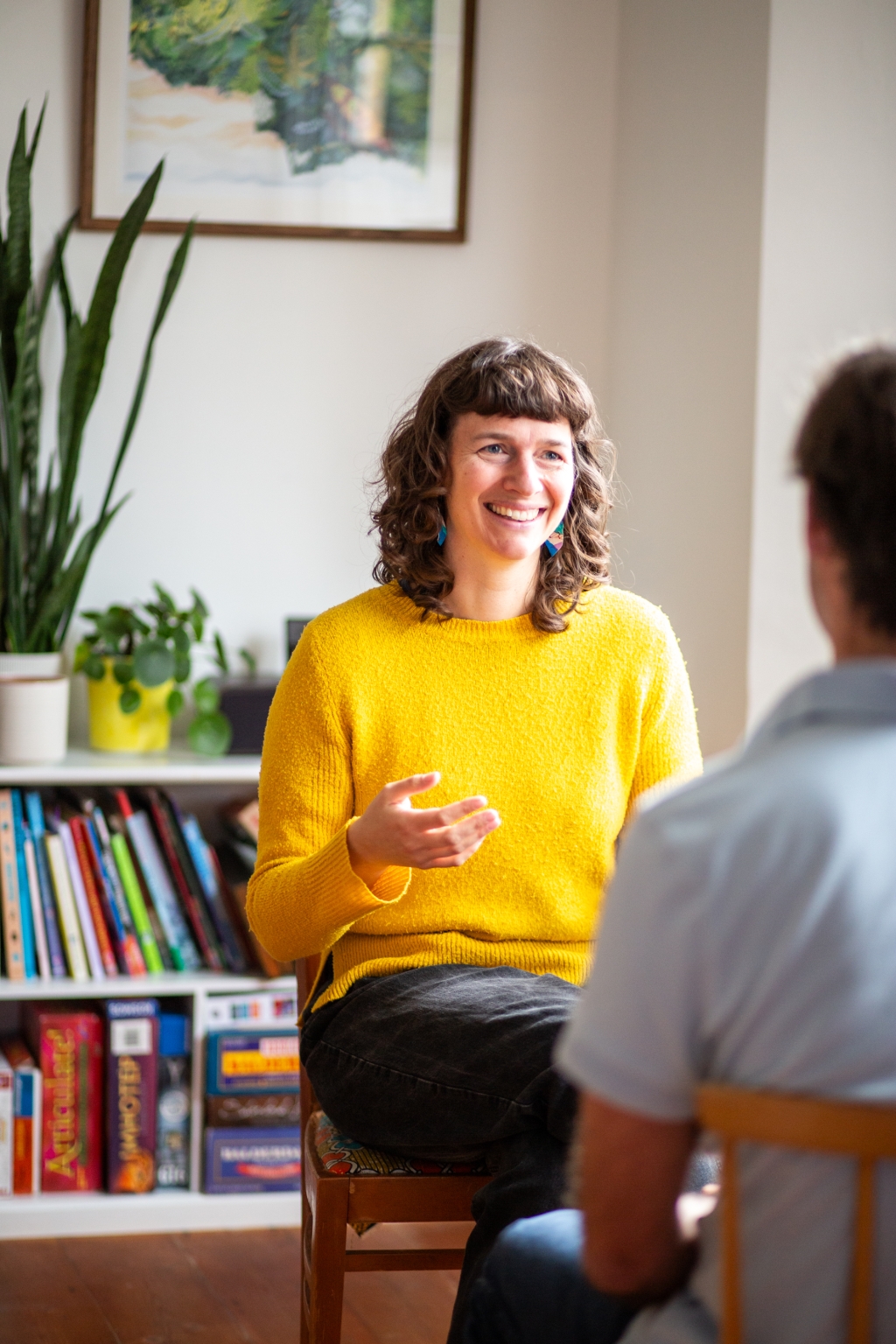 Sophie wearing a yellow jumper in discussion with a client who has their back to the camera