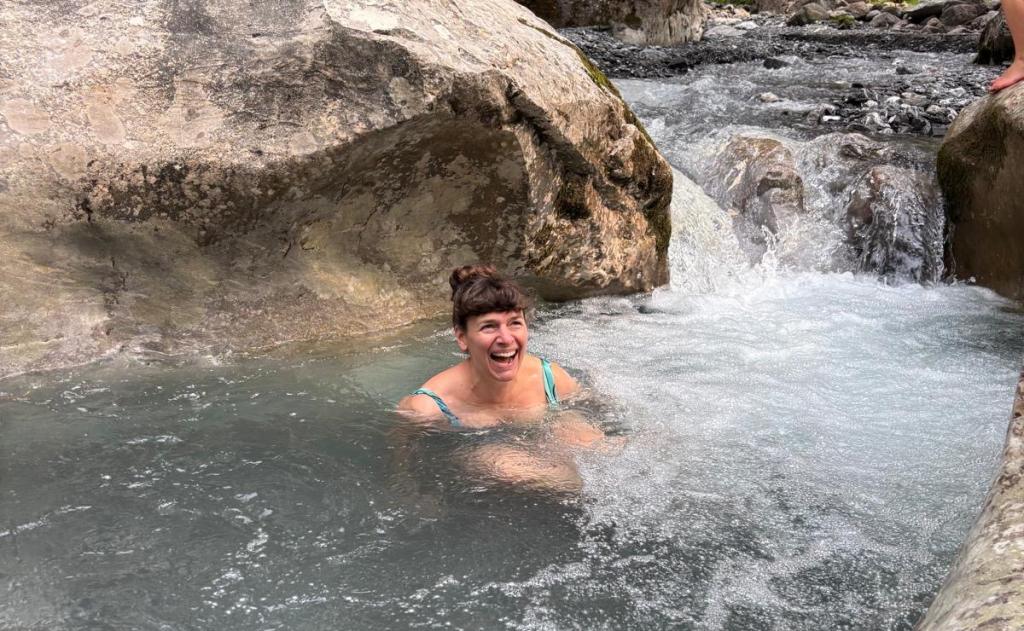 Sophie immersed in a cold water stream looking exhilarated